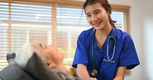 Blau gekleidete Pflegerin mit einem Stethoskop kümmert sich um Patienten
